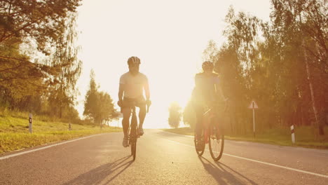 Steadicam-shot-of-mountain-biking-couple-riding-on-bike-trail-at-sunset-doing-high.